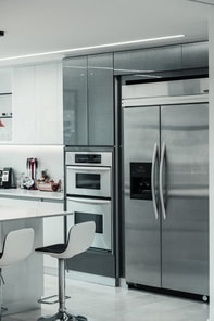 Photo of a stainless steel themed kitchen with refrigerator and oven
