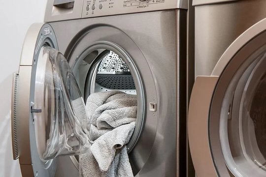 Photo of a partially open laundry machine with a towel hanging out 